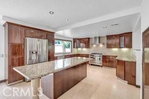 25152 Mammoth Cir, Lake Forest, CA 92630 - kitchen with appliances with stainless steel finishes, wall chimney exhaust hood, a center island, light stone countertops, and tasteful backsplash