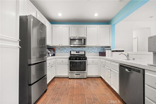1335 Mc Fadden Dr, Fullerton, CA 92833 - kitchen featuring stainless steel appliances, white cabinets, tile countertops, wood finished floors, and recessed lighting