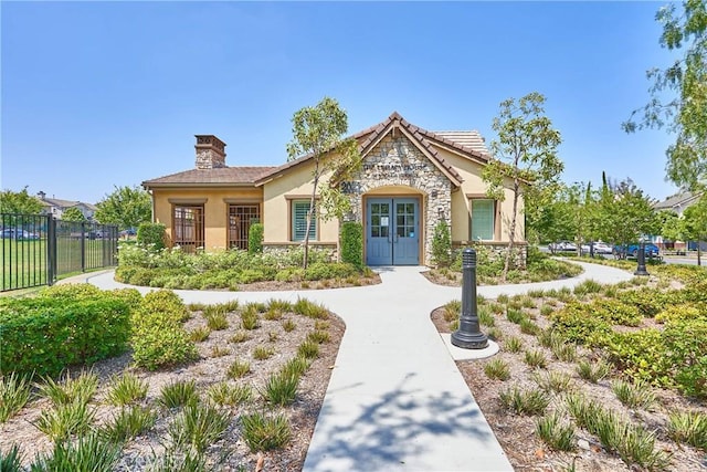1335 Mc Fadden Dr, Fullerton, CA 92833 - view of front facade with stucco siding, a chimney, stone siding, and french doors