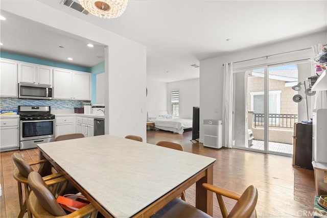 1335 Mc Fadden Dr, Fullerton, CA 92833 - kitchen featuring stainless steel appliances, wood finished floors, decorative backsplash, white cabinets, and recessed lighting