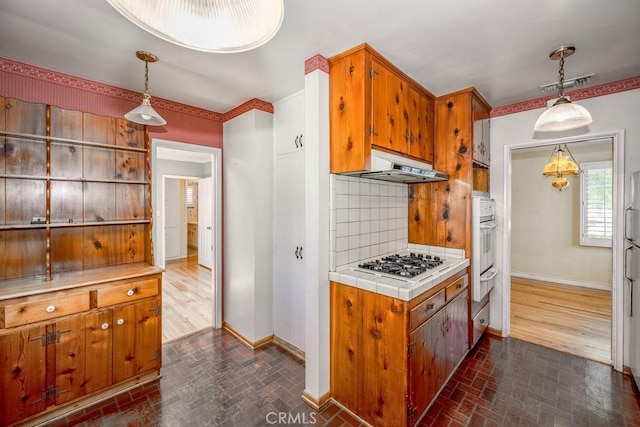 11009 Quill Ave, Sunland, CA 91040 - kitchen with brick patterned flooring, under cabinet range hood, decorative backsplash, gas stovetop, and brown cabinets
