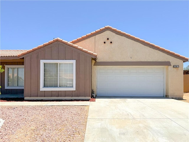 12967 Side Saddle Rd, Victorville, CA 92392 - view of front facade featuring driveway, board and batten siding, a tiled roof, and an attached garage