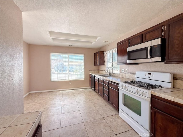 12967 Side Saddle Rd, Victorville, CA 92392 - kitchen with gas range gas stove, stainless steel microwave, plenty of natural light, dark brown cabinets, and a textured ceiling