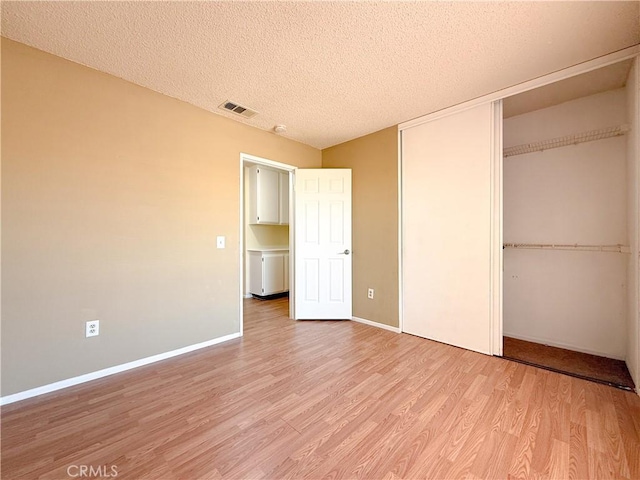 12967 Side Saddle Rd, Victorville, CA 92392 - unfurnished bedroom featuring a closet, light wood-style floors, and a textured ceiling