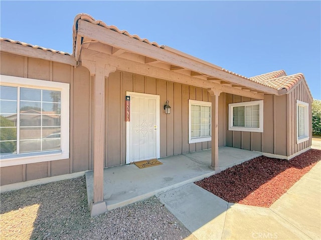12967 Side Saddle Rd, Victorville, CA 92392 - property entrance featuring a tile roof, board and batten siding, and covered porch