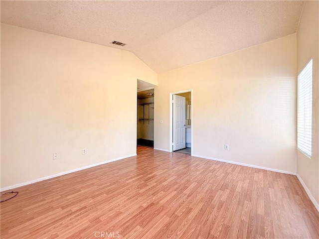 12967 Side Saddle Rd, Victorville, CA 92392 - empty room with light wood-type flooring, vaulted ceiling, and a textured ceiling