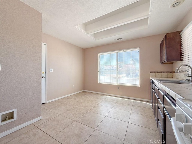 12967 Side Saddle Rd, Victorville, CA 92392 - kitchen with tile counters, light tile patterned floors, a textured ceiling, and dark brown cabinetry
