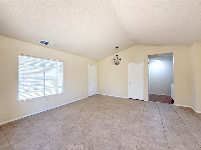 12967 Side Saddle Rd, Victorville, CA 92392 - unfurnished room with a textured ceiling, vaulted ceiling, light tile patterned floors, and a chandelier