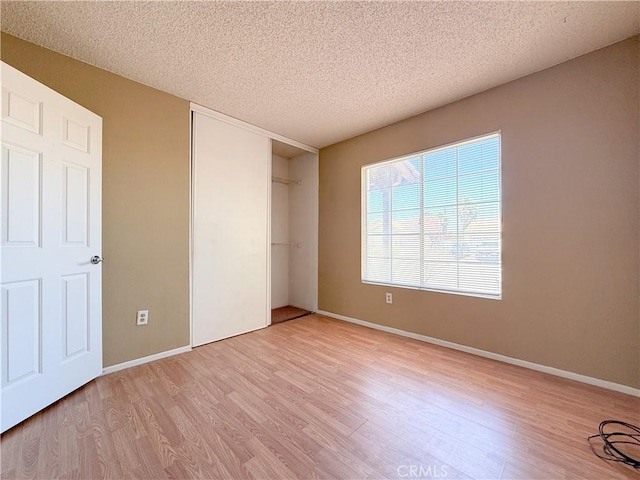 12967 Side Saddle Rd, Victorville, CA 92392 - unfurnished bedroom with light wood-style floors, a closet, and a textured ceiling