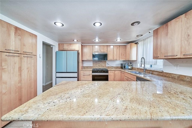 2424 S Gaffey St Unit 101, San Pedro, CA 90731 - kitchen featuring stainless steel microwave, freestanding refrigerator, black range with gas stovetop, light stone countertops, and a peninsula