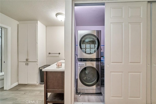 2424 S Gaffey St Unit 101, San Pedro, CA 90731 - laundry area with stacked washer and clothes dryer, light wood-type flooring, and a textured ceiling