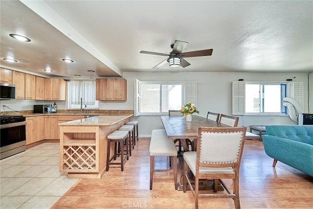 2424 S Gaffey St Unit 101, San Pedro, CA 90731 - kitchen featuring stainless steel appliances, light brown cabinets, a kitchen bar, ceiling fan, and open floor plan