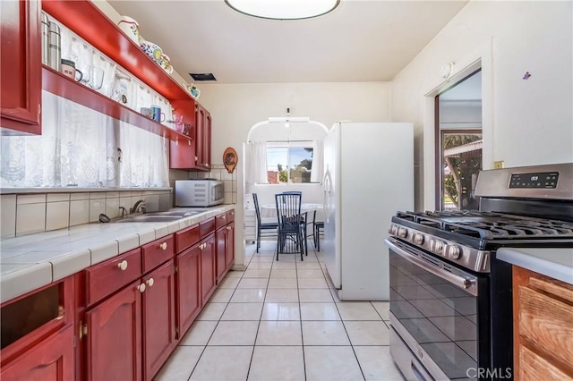 2439 California St, Walnut Park, CA 90255 - kitchen featuring white appliances, reddish brown cabinets, tile countertops, and light tile patterned floors