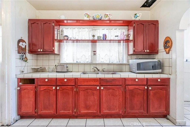 2439 California St, Walnut Park, CA 90255 - kitchen featuring stainless steel microwave, reddish brown cabinets, and decorative backsplash