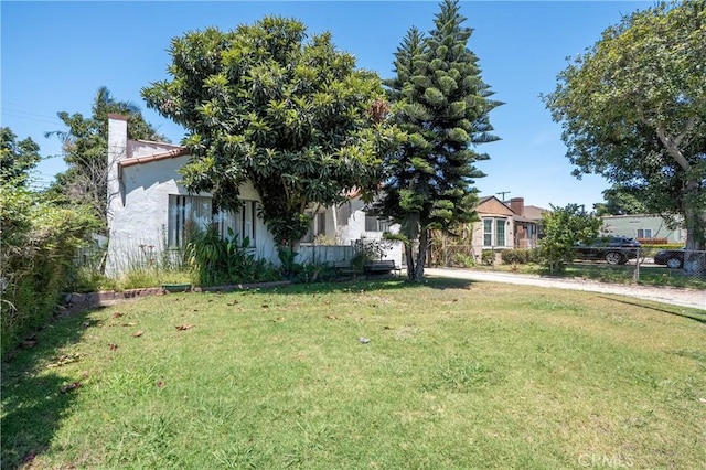 2439 California St, Walnut Park, CA 90255 - view of property hidden behind natural elements with a front lawn, stucco siding, and a chimney
