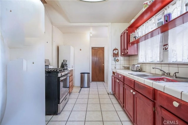 2439 California St, Walnut Park, CA 90255 - kitchen featuring stainless steel range with gas cooktop, dark brown cabinets, tasteful backsplash, and light tile patterned floors