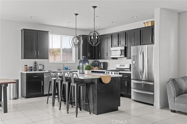 4443 Manzanita St, Guadalupe, CA 93434 - kitchen featuring appliances with stainless steel finishes, dark cabinetry, light countertops, a kitchen island, and a kitchen breakfast bar