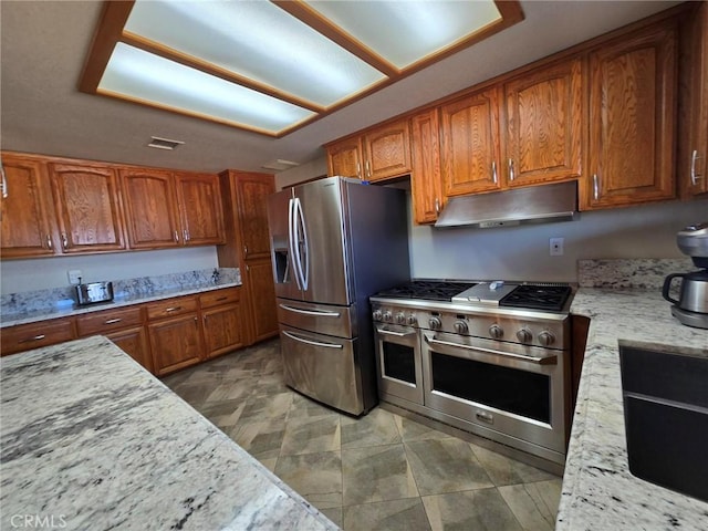 7050 Ivanpah Ave Unit 29, Palms, CA 92277 - kitchen with stainless steel appliances, under cabinet range hood, brown cabinetry, and light stone countertops