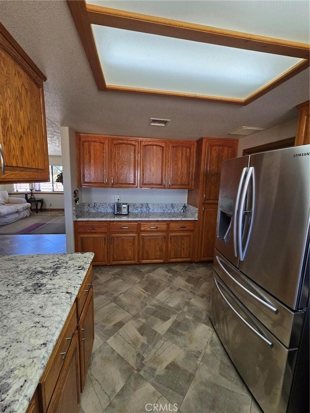 7050 Ivanpah Ave Unit 29, Palms, CA 92277 - kitchen with stainless steel fridge, brown cabinetry, and light stone countertops