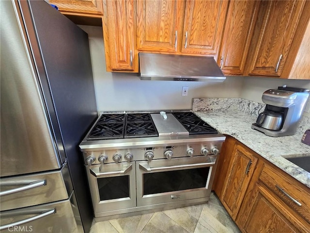 7050 Ivanpah Ave Unit 29, Palms, CA 92277 - kitchen with appliances with stainless steel finishes, under cabinet range hood, light stone counters, and brown cabinetry