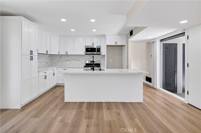 7364 Layton St, Rancho Cucamonga, CA 91730 - kitchen with stainless steel microwave, range, white cabinetry, a center island with sink, and recessed lighting
