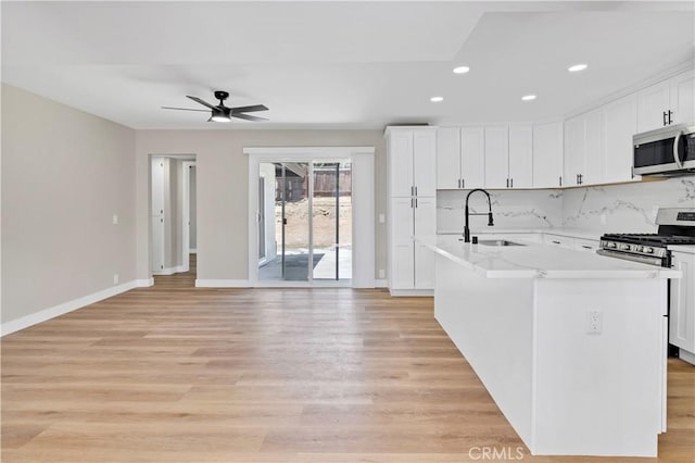 7364 Layton St, Rancho Cucamonga, CA 91730 - kitchen featuring appliances with stainless steel finishes, light wood finished floors, a kitchen island with sink, light countertops, and recessed lighting