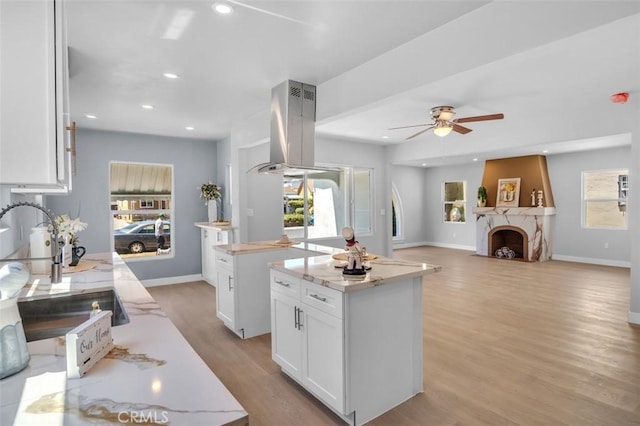 2049 W 71st St, Los Angeles, CA 90047 - kitchen featuring island exhaust hood, a ceiling fan, white cabinets, light wood-style floors, and healthy amount of natural light
