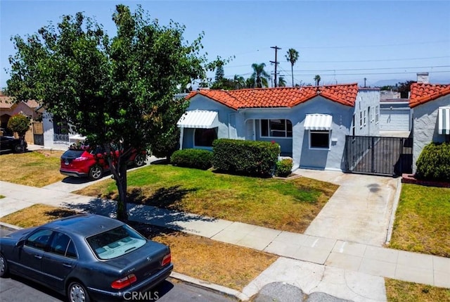 2049 W 71st St, Los Angeles, CA 90047 - mediterranean / spanish-style house featuring a tiled roof, stucco siding, and a front lawn