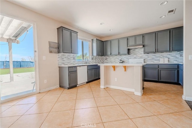 11818 Forest Park Ln, Victorville, CA 92392 - kitchen featuring dishwasher, gray cabinets, backsplash, light countertops, and a breakfast bar area