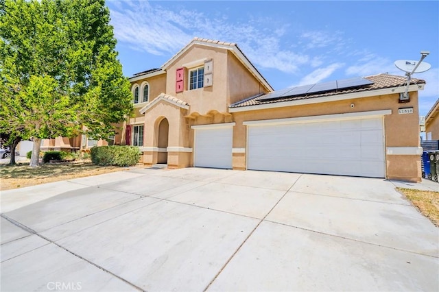 11818 Forest Park Ln, Victorville, CA 92392 - mediterranean / spanish-style home with roof mounted solar panels, stucco siding, concrete driveway, a tile roof, and an attached garage