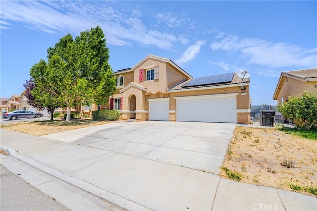 11818 Forest Park Ln, Victorville, CA 92392 - mediterranean / spanish home featuring stucco siding, roof mounted solar panels, concrete driveway, and an attached garage