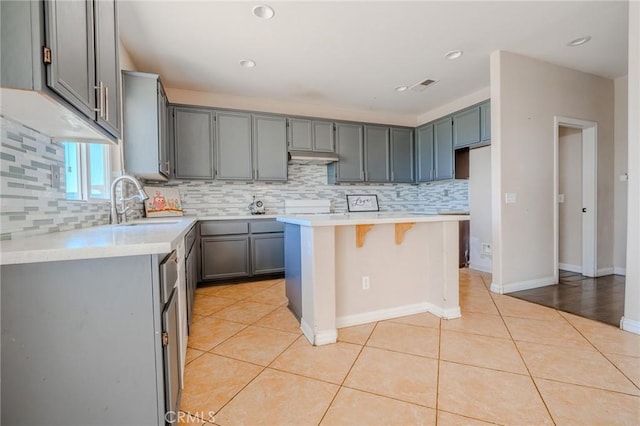 11818 Forest Park Ln, Victorville, CA 92392 - kitchen with backsplash, a breakfast bar area, gray cabinets, light tile patterned floors, and recessed lighting