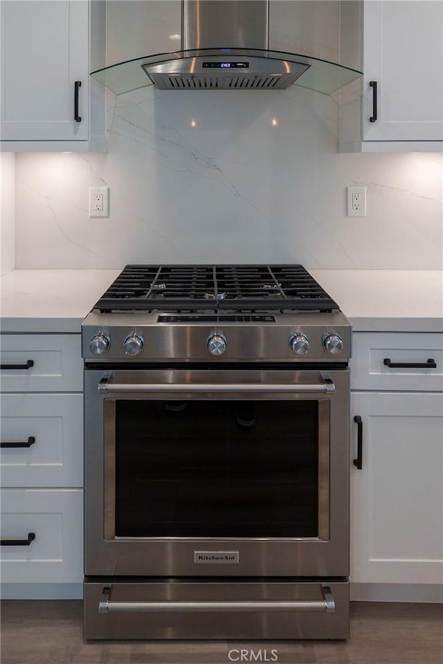 8645 Butte Cir Unit 603C, Huntington Beach, CA 92646 - kitchen with stainless steel gas stove, extractor fan, light countertops, decorative backsplash, and white cabinetry