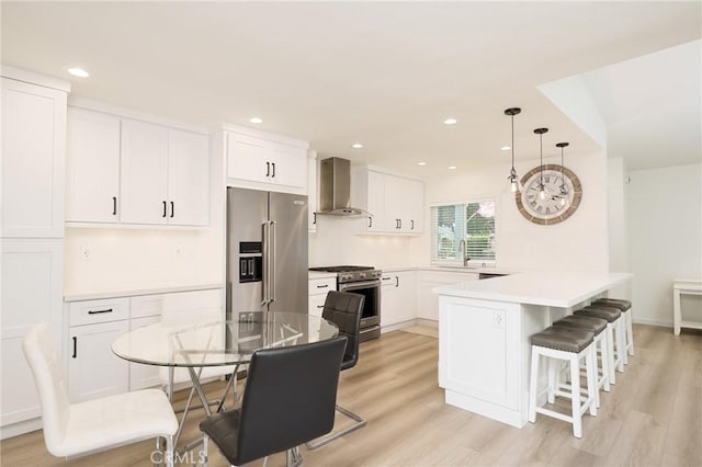 8645 Butte Cir Unit 603C, Huntington Beach, CA 92646 - kitchen with high end appliances, wall chimney range hood, a breakfast bar, a peninsula, and white cabinets