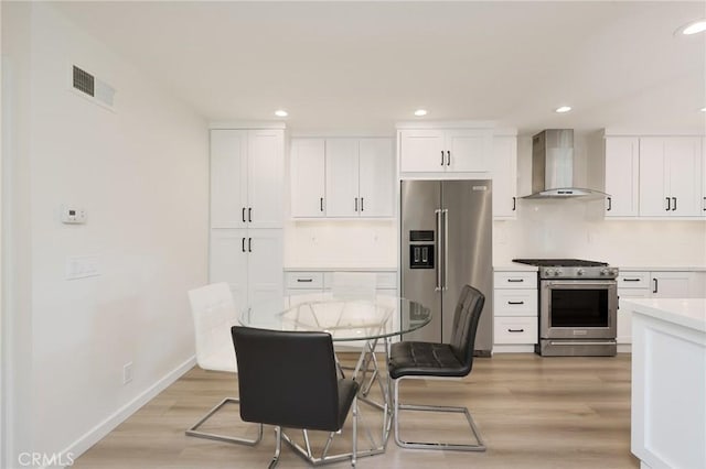 8645 Butte Cir Unit 603C, Huntington Beach, CA 92646 - kitchen featuring high end appliances, wall chimney exhaust hood, light wood finished floors, white cabinets, and light countertops