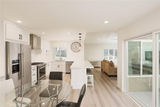 8645 Butte Cir Unit 603C, Huntington Beach, CA 92646 - kitchen with premium appliances, wall chimney exhaust hood, light wood finished floors, a breakfast bar, and healthy amount of natural light