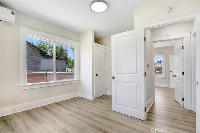 293 E Congress St, Colton, CA 92324 - unfurnished bedroom featuring a wall mounted air conditioner, multiple windows, and light wood finished floors