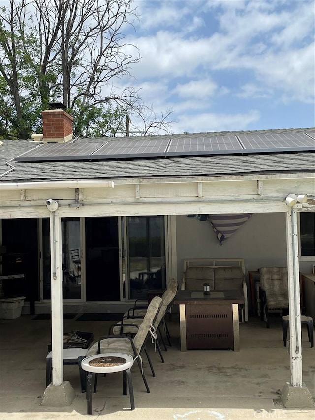 7957 Sausalito Ave, West Hills, CA 91304 - rear view of house featuring a shingled roof, a patio, roof mounted solar panels, and a chimney