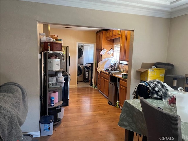 13213 Leffingwell Rd, Whittier, CA 90605 - kitchen featuring estacked washer and dryer, crown molding, light wood-style flooring, and brown cabinets
