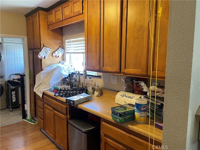13213 Leffingwell Rd, Whittier, CA 90605 - kitchen featuring stacked washer and clothes dryer, brown cabinetry, light wood-style flooring, and light countertops