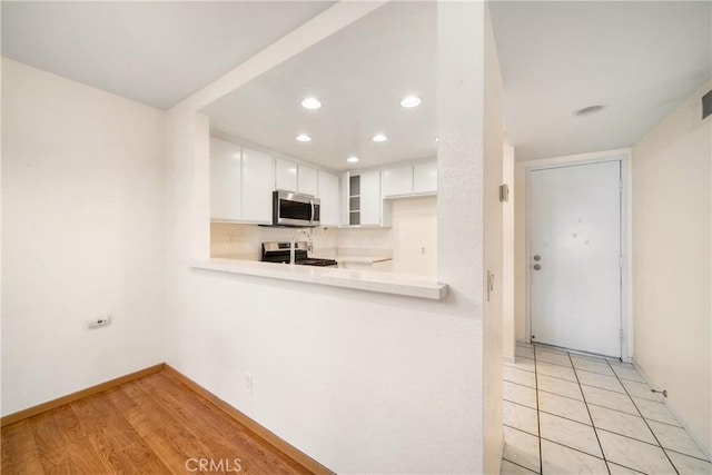 12277 Foster Rd, Norwalk, CA 90650 - kitchen featuring stainless steel microwave, range with electric cooktop, light countertops, recessed lighting, and white cabinets