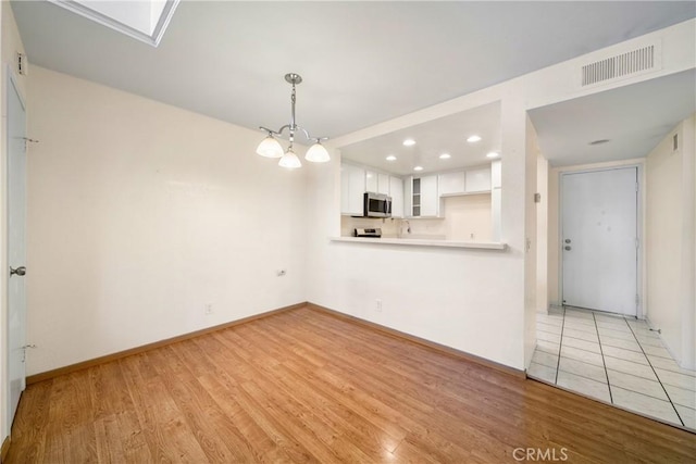 12277 Foster Rd, Norwalk, CA 90650 - unfurnished living room featuring light wood-type flooring, a chandelier, and recessed lighting