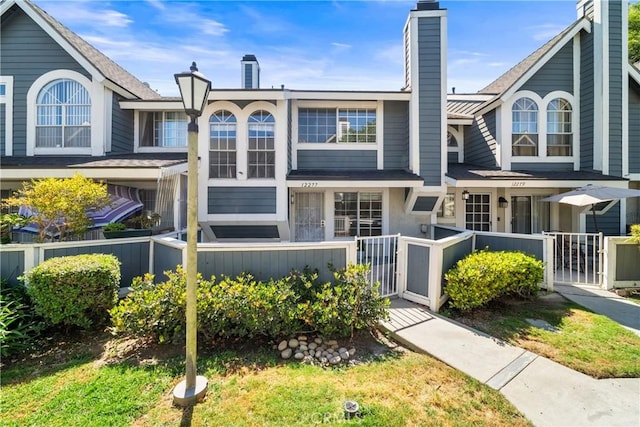 12277 Foster Rd, Norwalk, CA 90650 - view of front of property featuring a gate, a chimney, a fenced front yard, and stucco siding