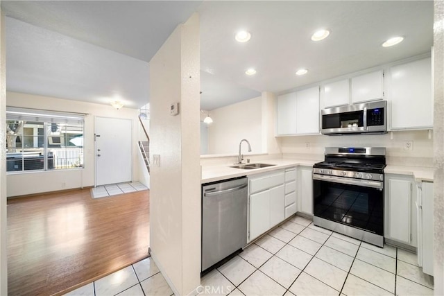 12277 Foster Rd, Norwalk, CA 90650 - kitchen with appliances with stainless steel finishes, light countertops, white cabinetry, light tile patterned floors, and recessed lighting