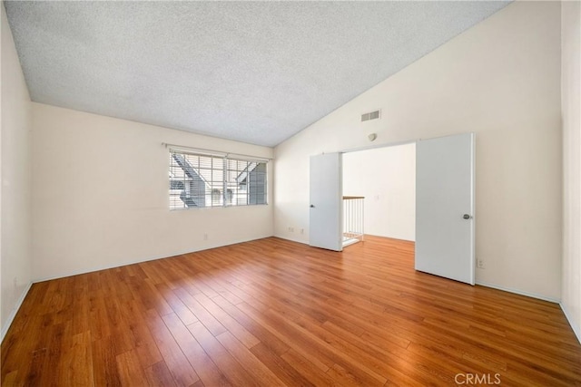 12277 Foster Rd, Norwalk, CA 90650 - unfurnished room with a textured ceiling, lofted ceiling, and hardwood / wood-style flooring