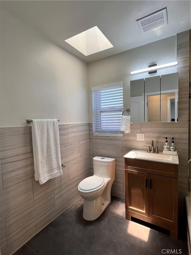 1610 266th St, Harbor City, CA 90710 - bathroom with tile walls, a skylight, vanity, tile patterned flooring, and wainscoting