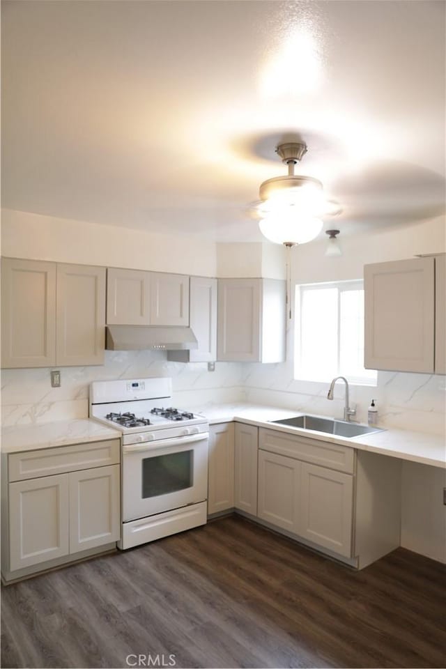 15154 Oliva Ave, Paramount, CA 90723 - kitchen with white range with gas stovetop, backsplash, under cabinet range hood, dark wood finished floors, and light countertops