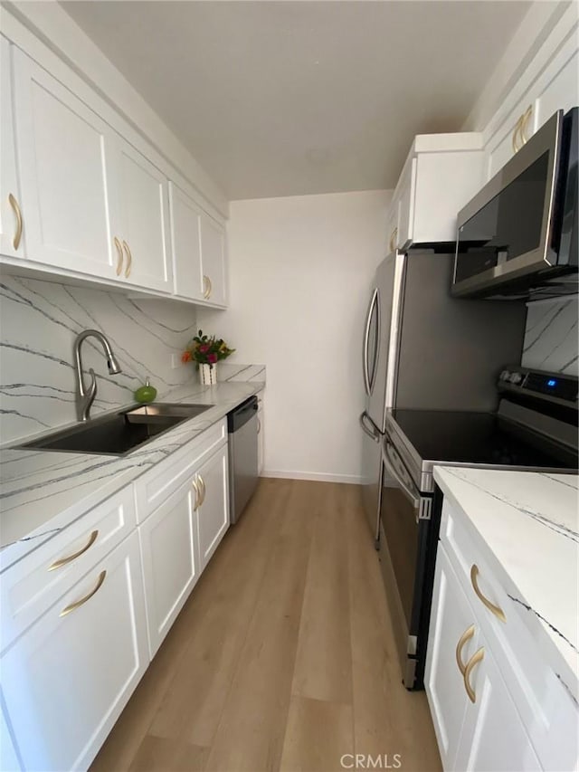 1640 Neil Armstrong St Unit 306, Montebello, CA 90640 - kitchen with stainless steel appliances, white cabinetry, light stone countertops, and light wood finished floors