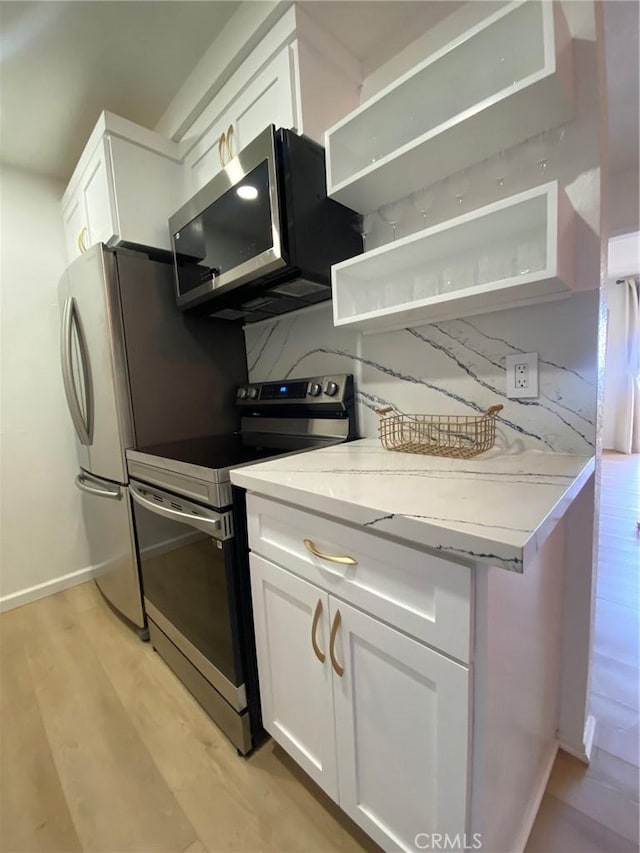 1640 Neil Armstrong St Unit 306, Montebello, CA 90640 - kitchen with appliances with stainless steel finishes, white cabinetry, light stone countertops, light wood-type flooring, and open shelves