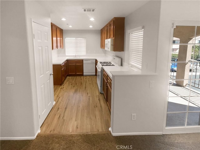 15617 Lasselle St Unit 31, Moreno Valley, CA 92551 - kitchen featuring white appliances, light countertops, brown cabinetry, light wood finished floors, and recessed lighting